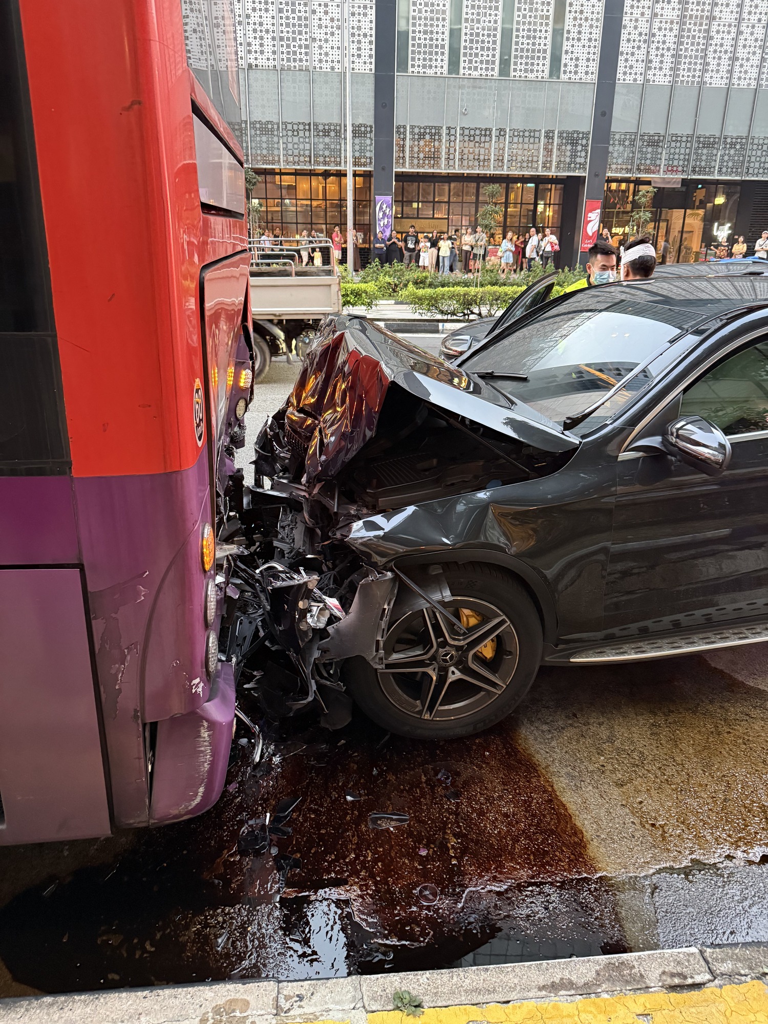 Crumpled bonnet of a Mercedes against the rear of a bus.