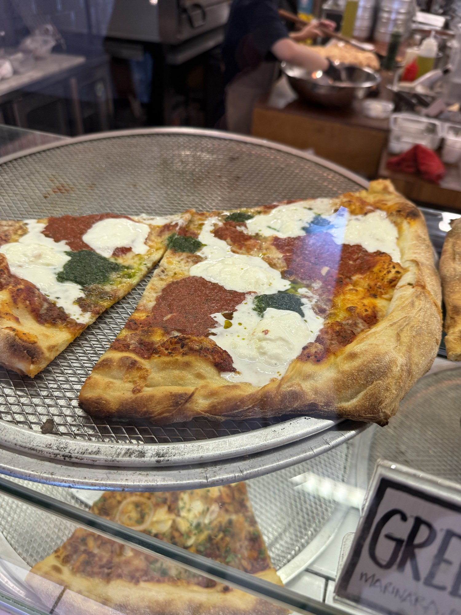 Large pizza slices topped with tomato sauce, green pesto and creamy cheese in the Choice Cuts display