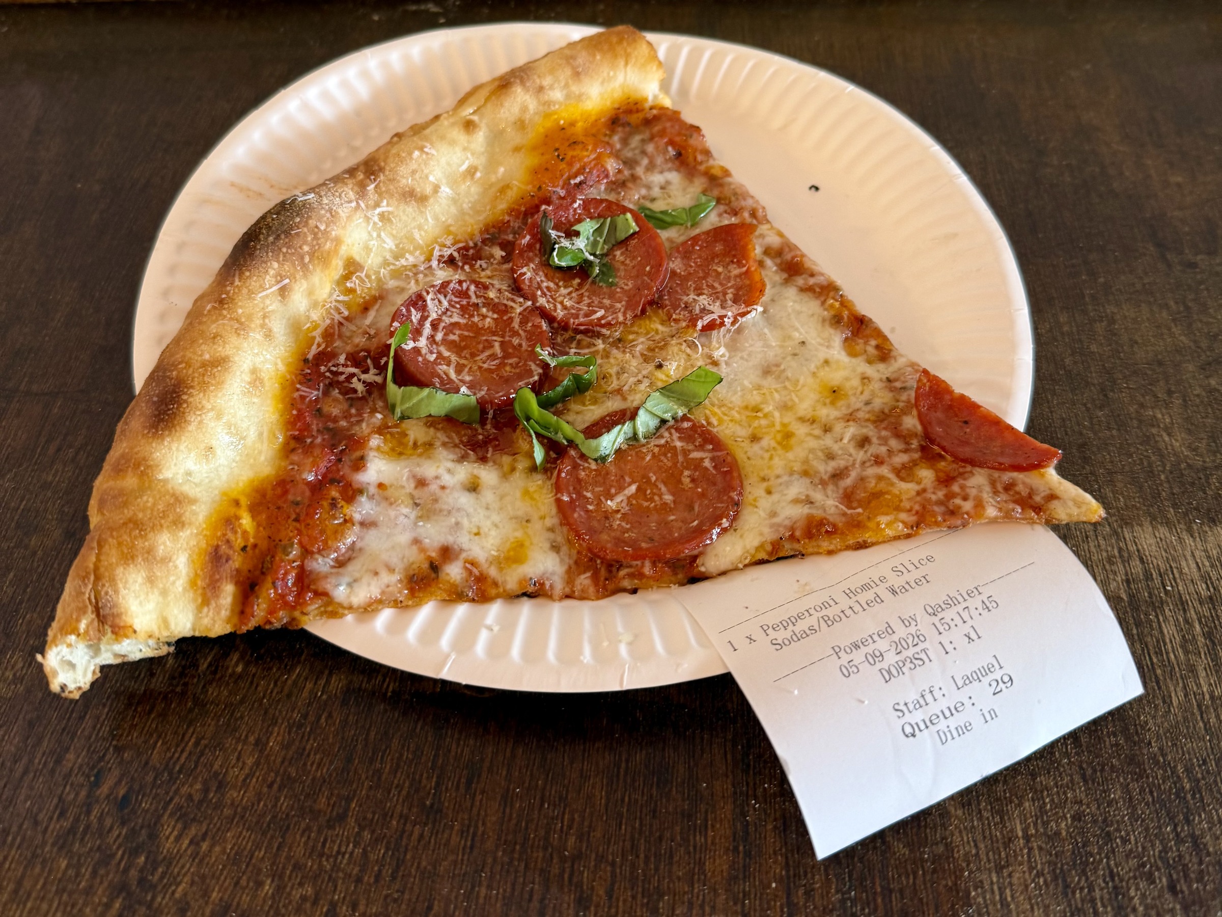 Pepperoni pizza slice with fresh herbs on a paper plate at Choice Cuts