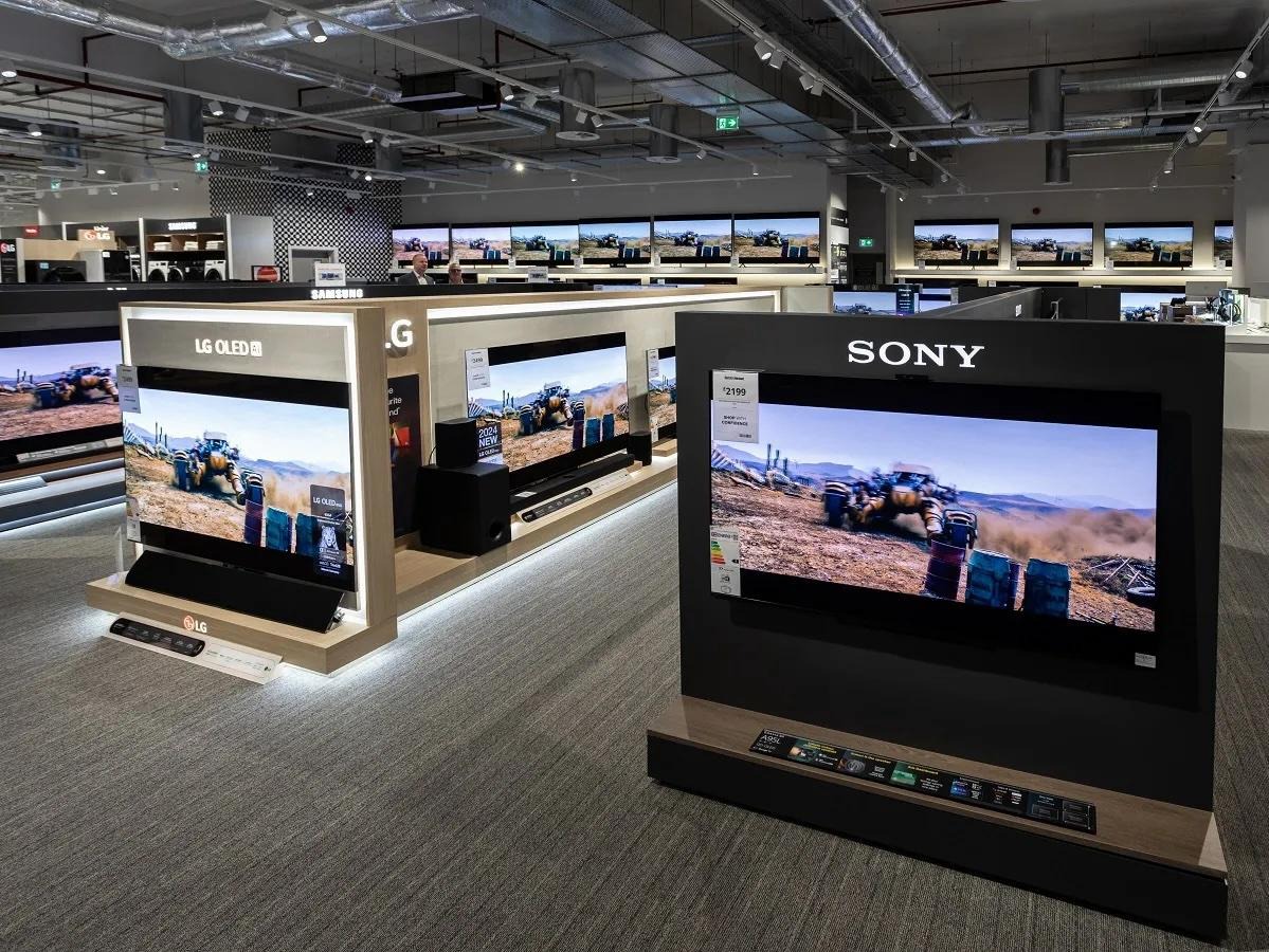 Television and sound-system displays with price labels in an electronics shop.