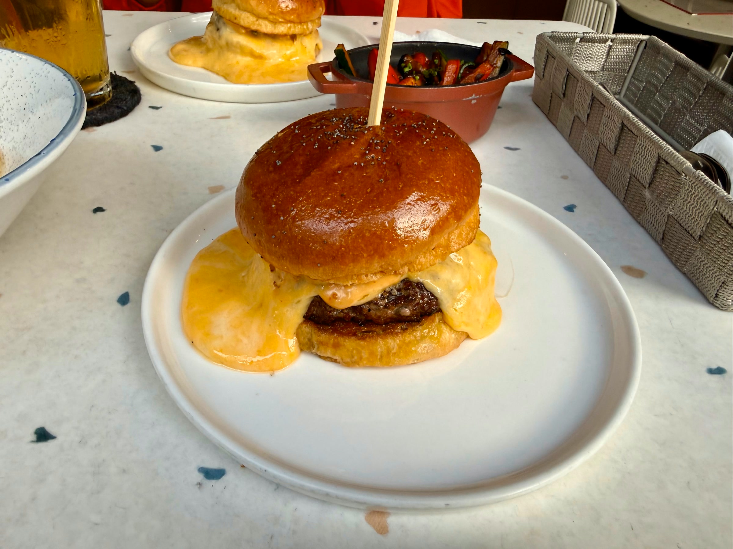 Wildfire Ultimate Cheeseburger on a white plate, with five-cheese melt spilling from a glossy brioche bun