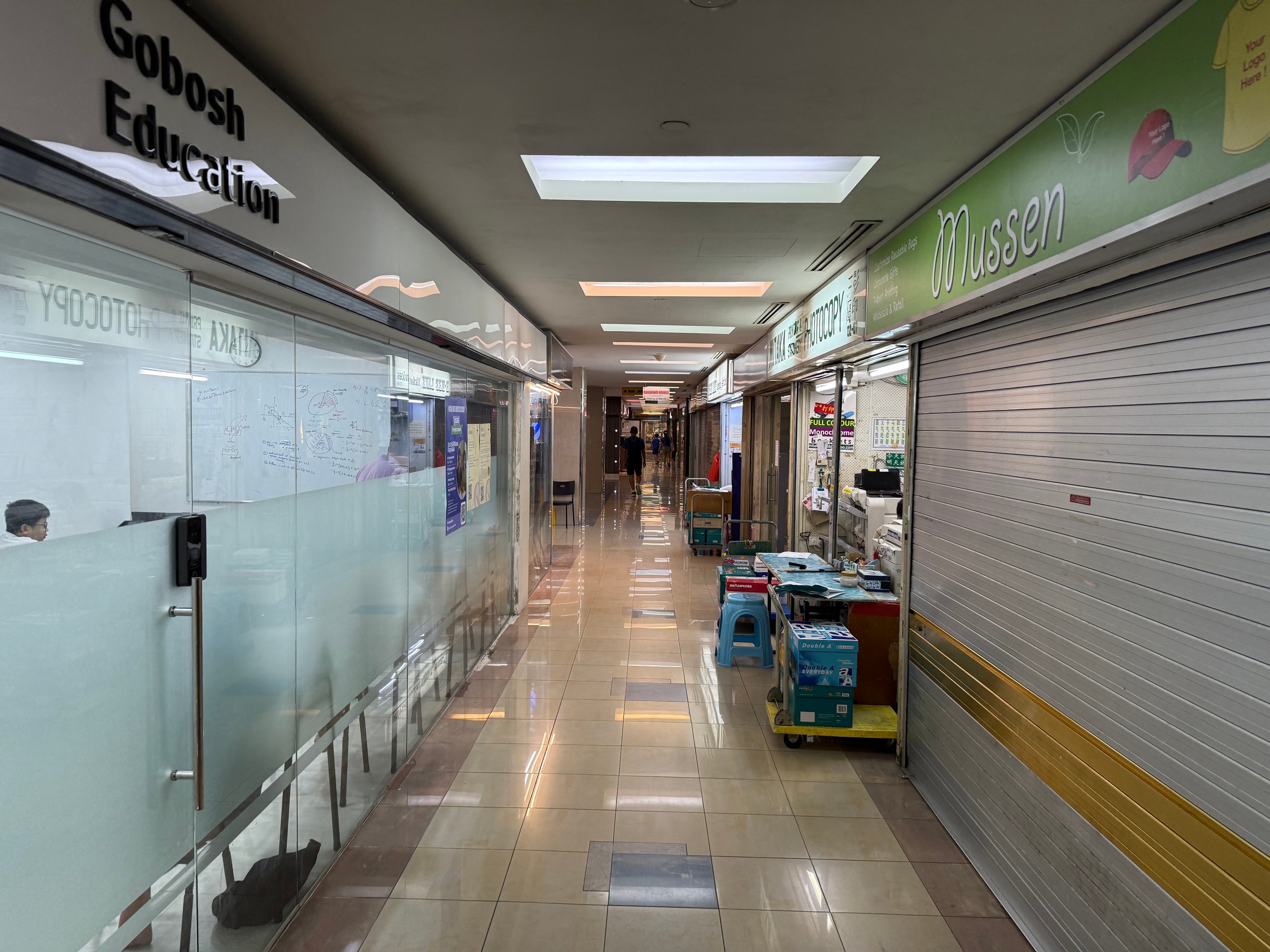 A long corridor lined with small shops and closed shutters.