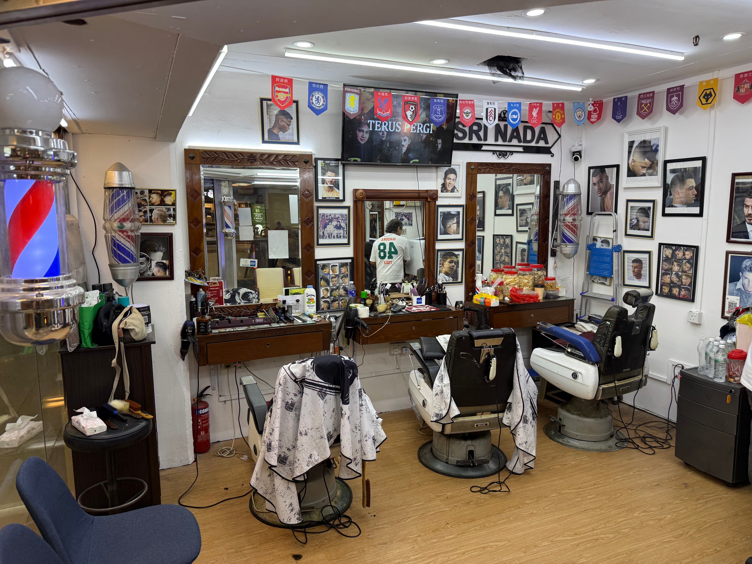 Barber chairs, mirrors and photographs inside Sri Nada barber shop.