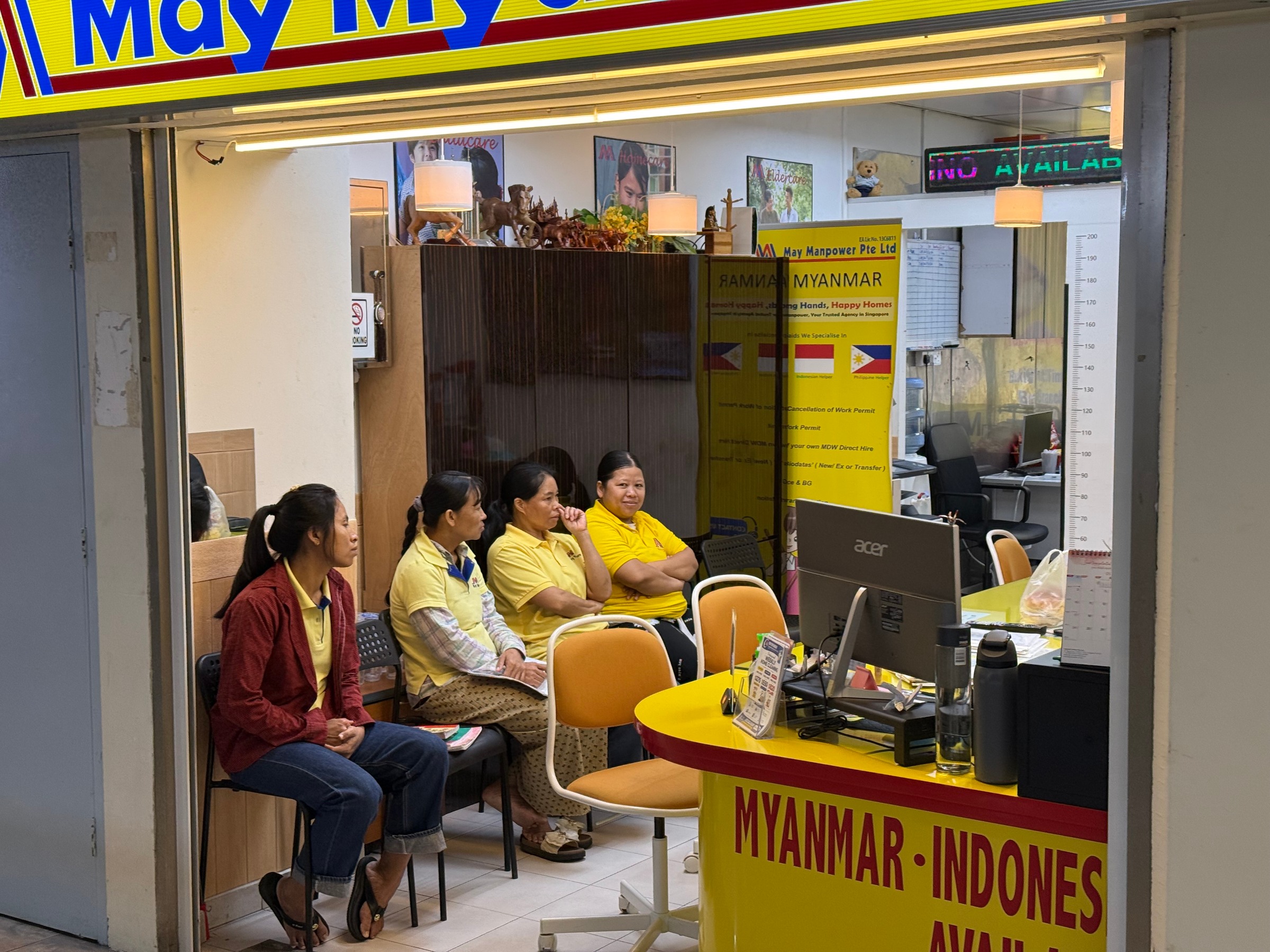 Women wearing yellow shirts seated inside May Manpower employment agency.