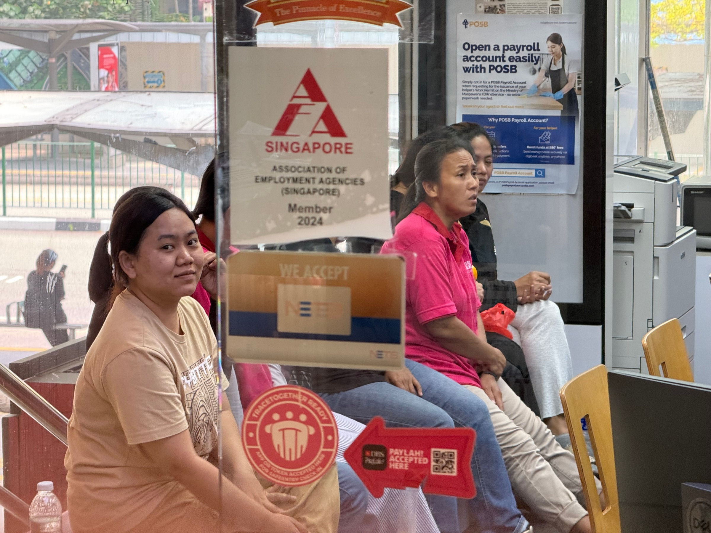 Women seated behind the glass at Crislo employment agency, one looking towards the camera.
