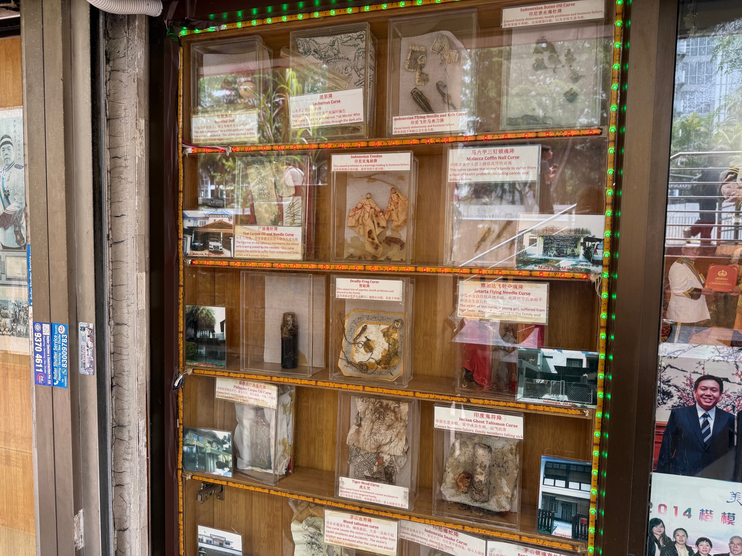 Objects and labels describing alleged curses in a glass display cabinet.