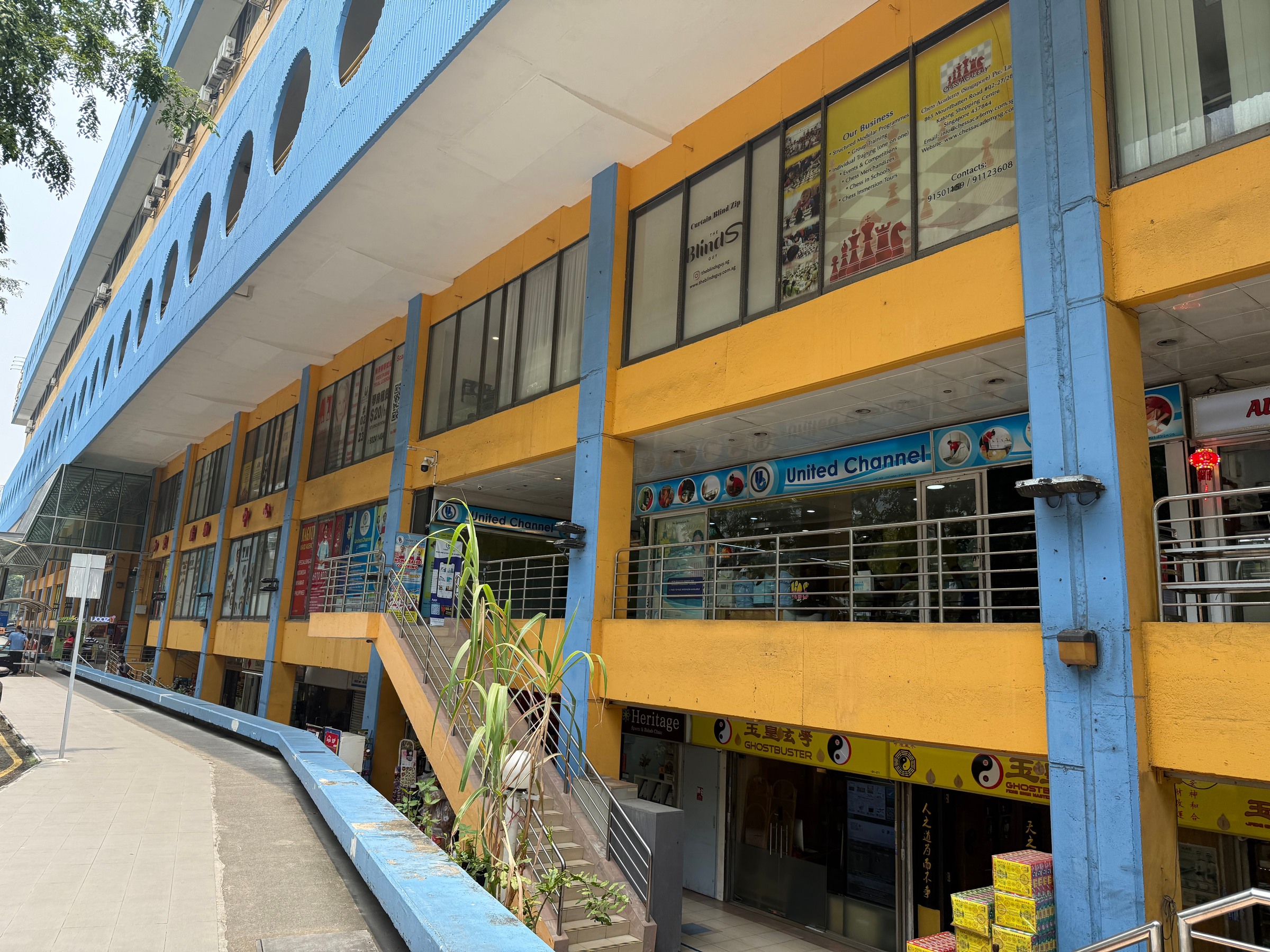 A view along the blue-and-yellow facade, with round windows above the columns.
