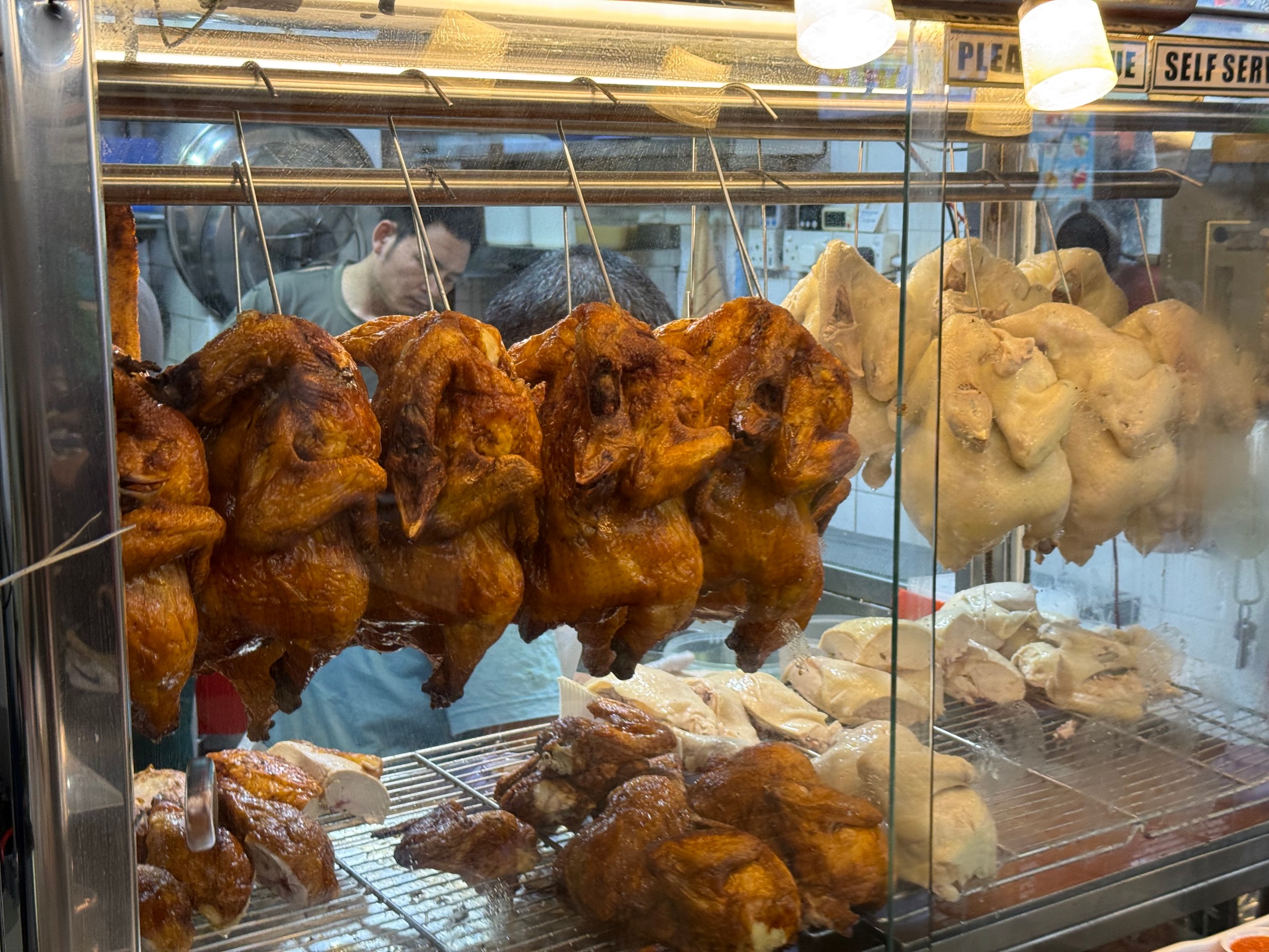 Cooked chickens hanging in rows in the stall display.