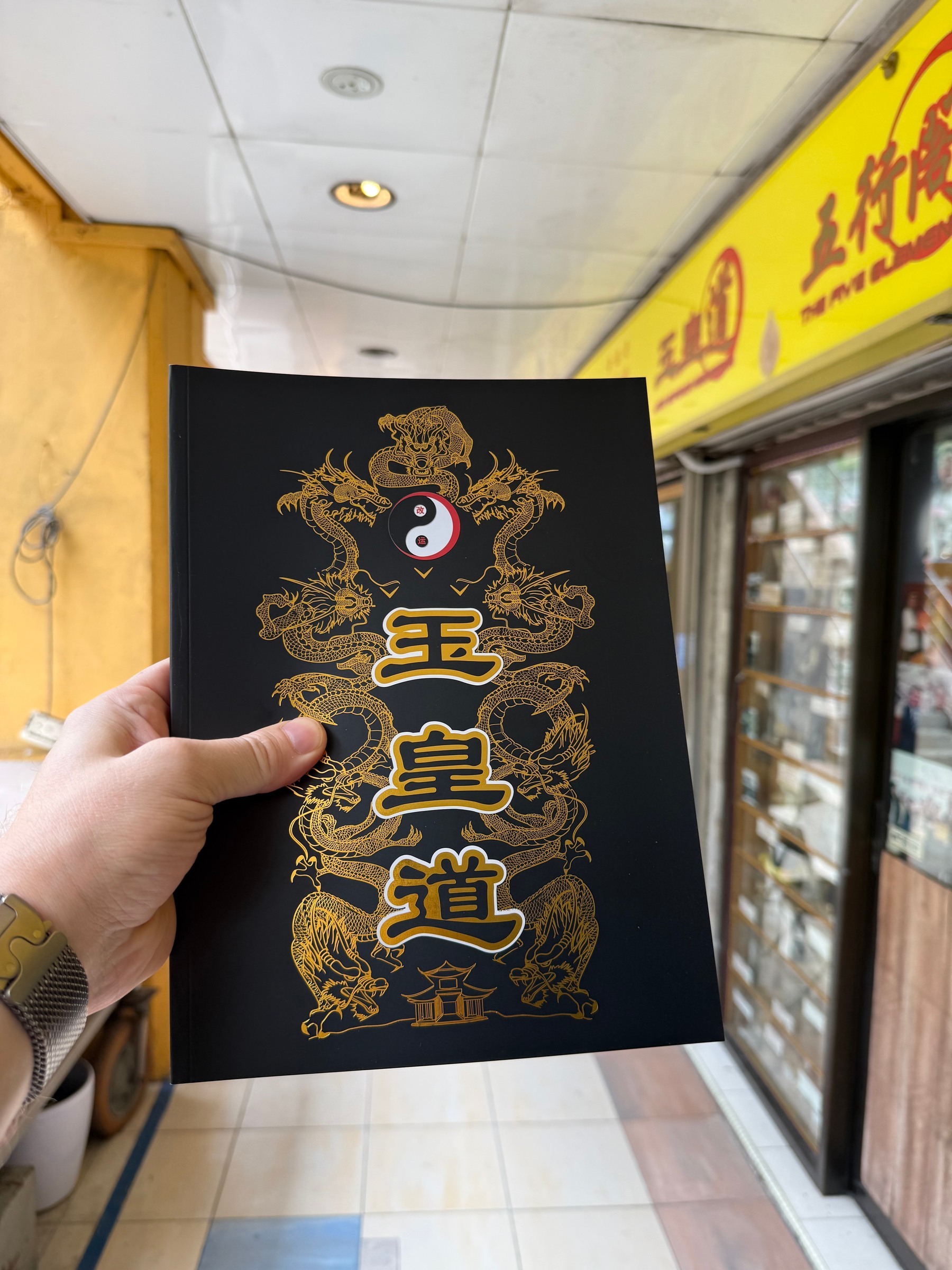 A hand holds a black book with gold lettering outside GHOSTBUSTER.