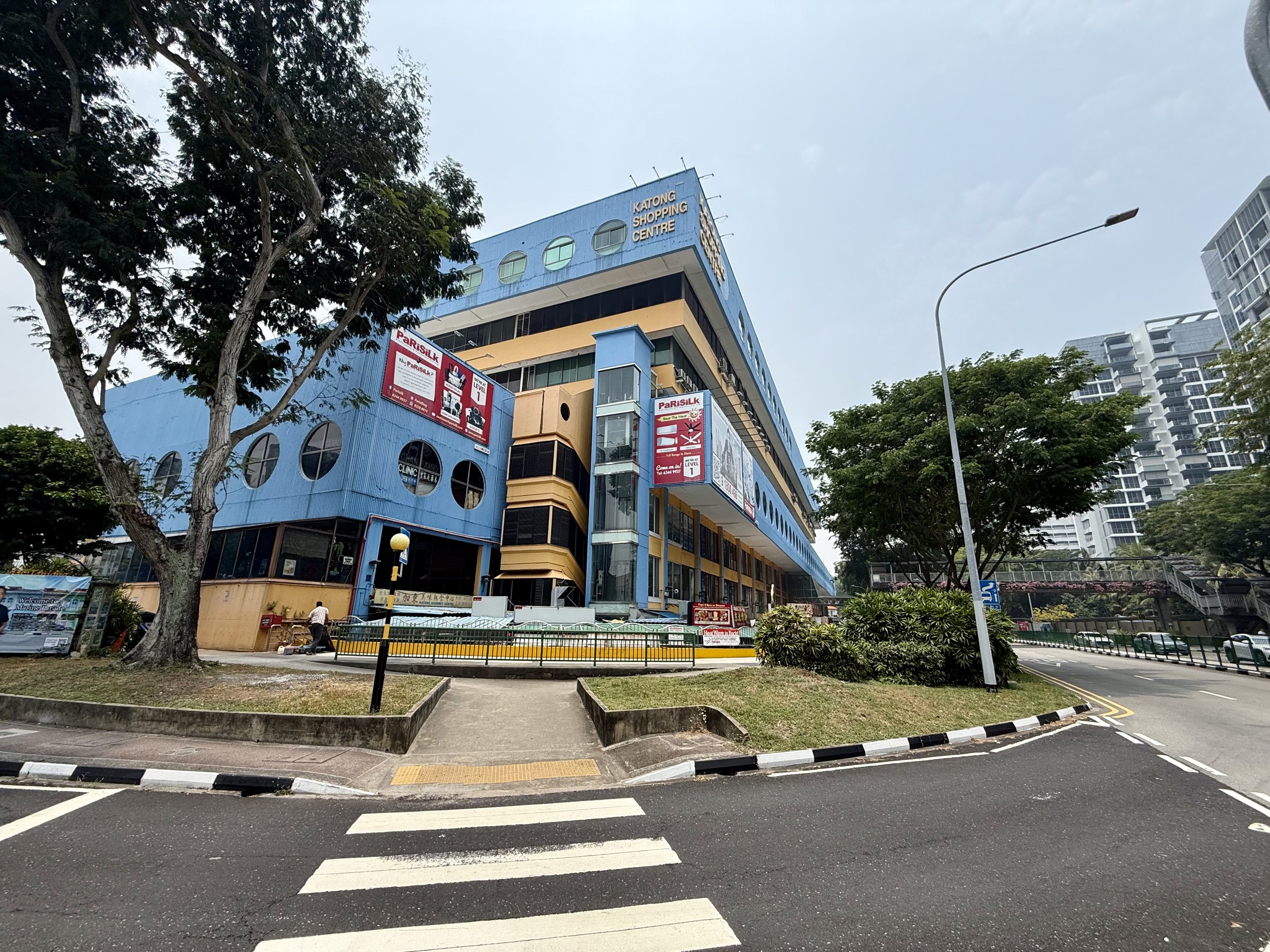 Blue-and-yellow Katong Shopping Centre beside the zebra crossing at the four-road junction.