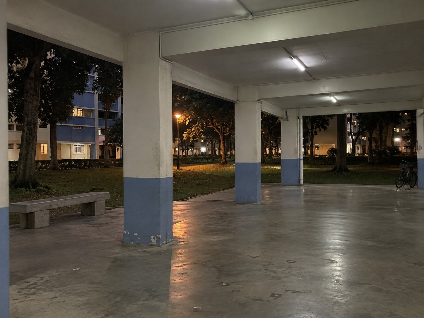 Open ground floor of an HDB block after dark