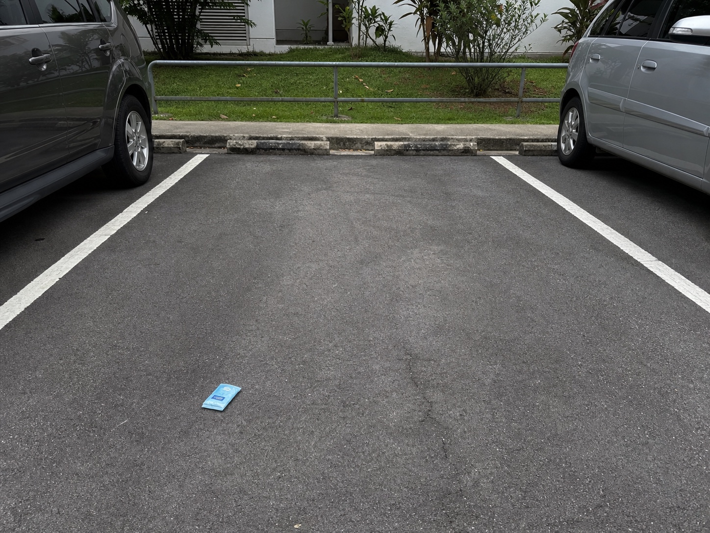 An empty Singapore parking space reserved by a small blue pocket tissue packet