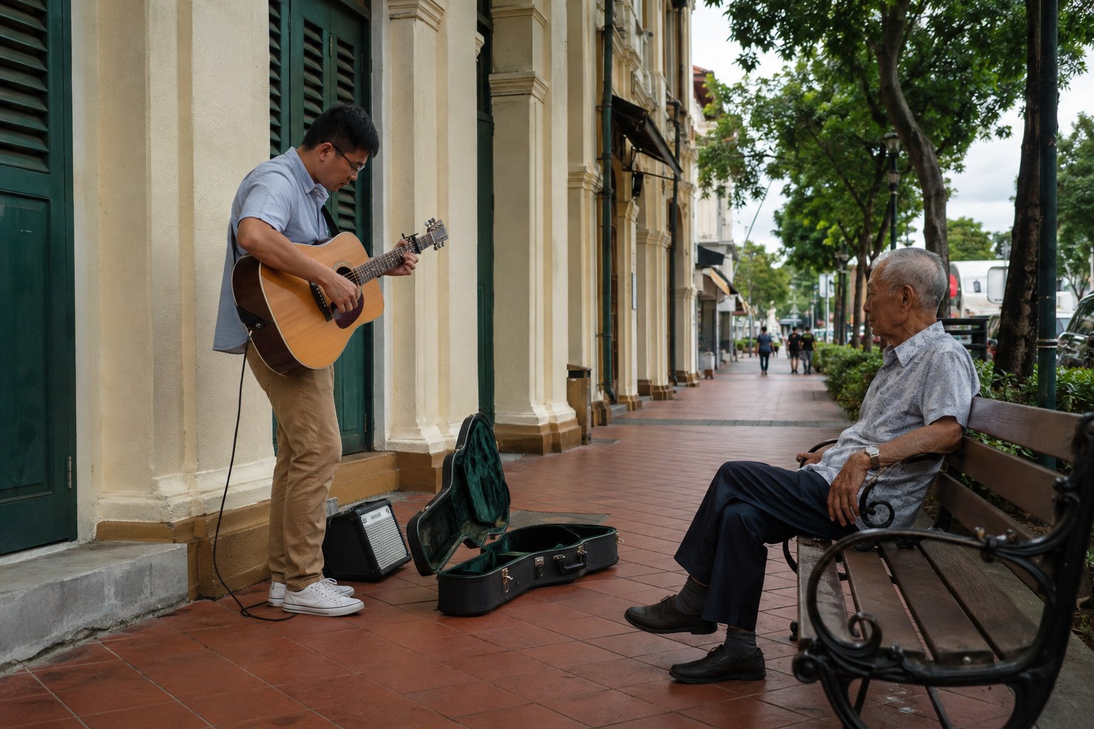 A guitarist playing for one attentive listener beside shophouses.