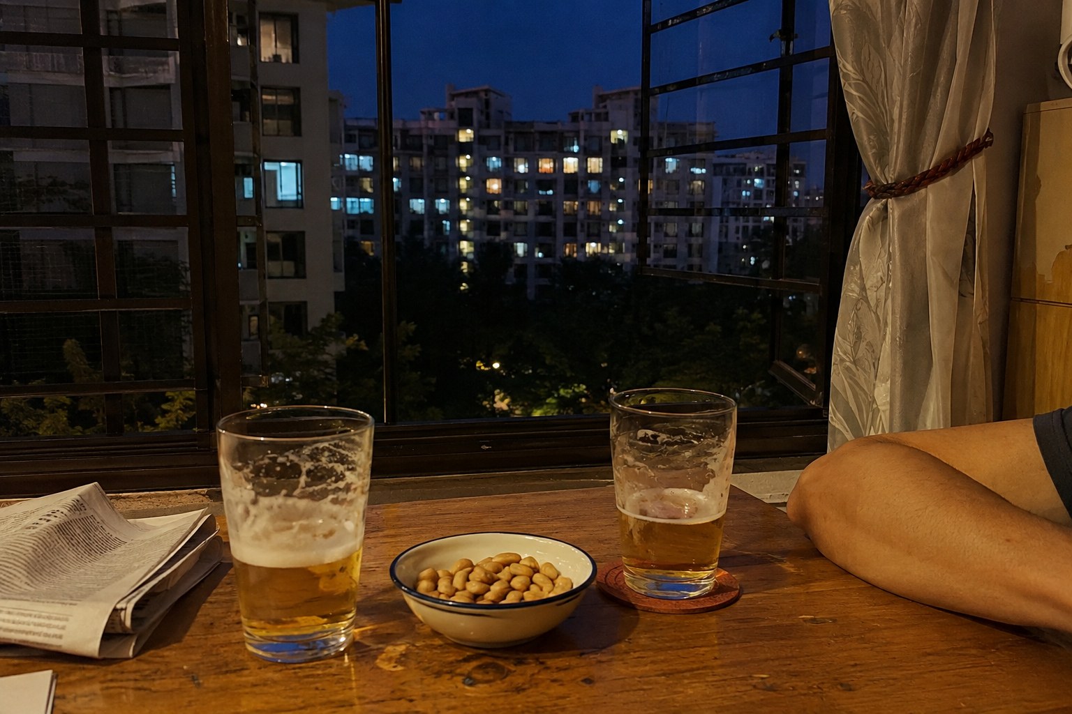 Two partly finished beers on a table inside an apartment at night.