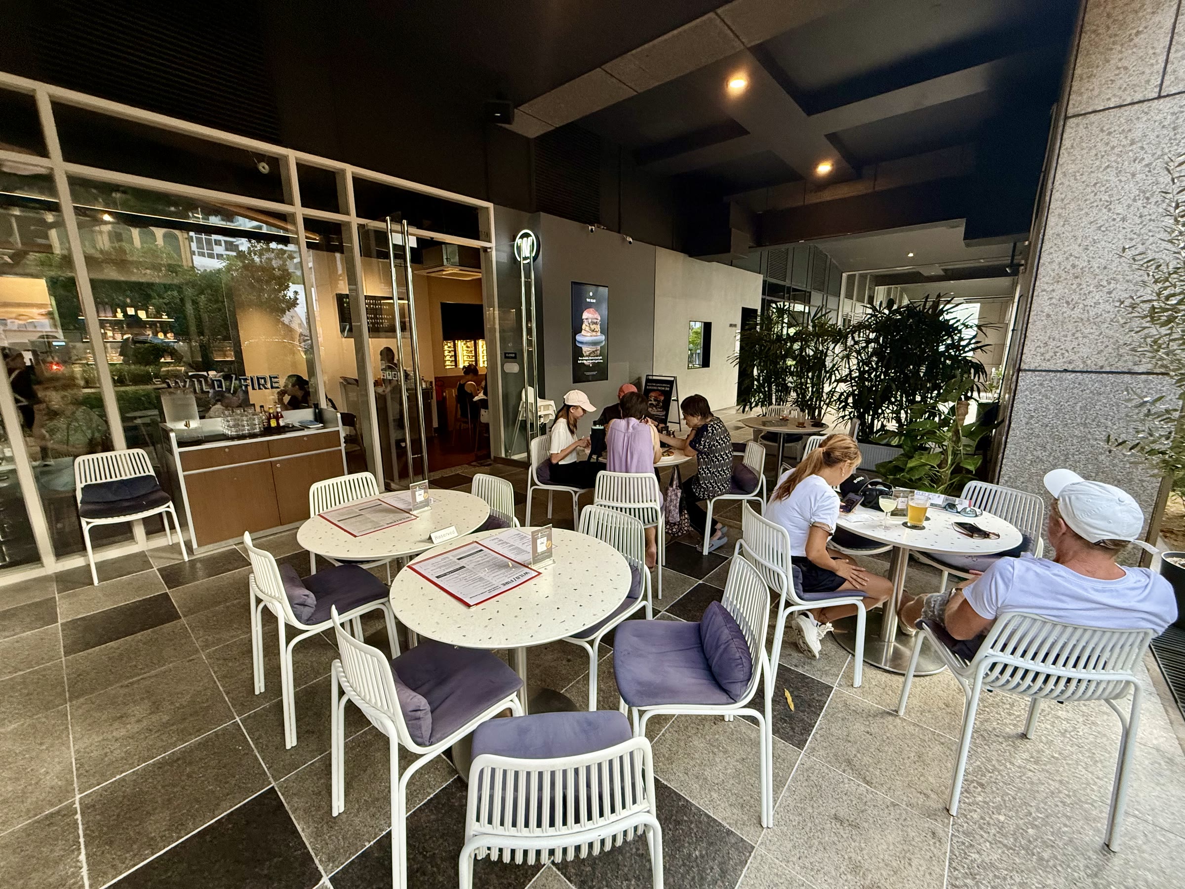 Covered veranda at Wildfire with white tables and chairs beside the restaurant entrance