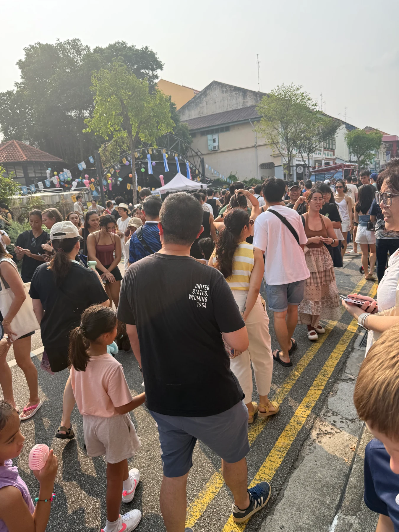 A dense crowd walks along Joo Chiat Road near the music area.