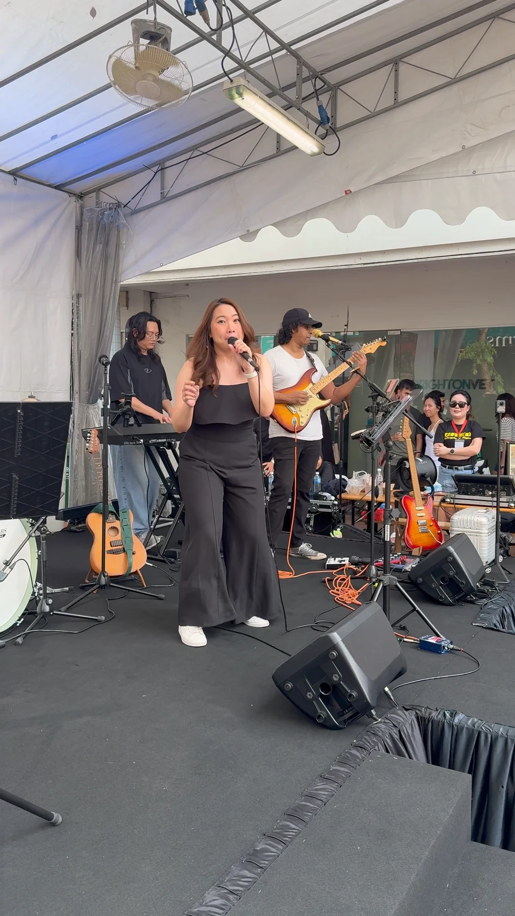A singer and band perform on a small covered stage at Katong Point.