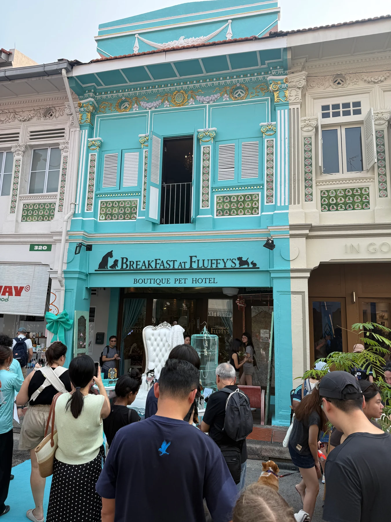 A turquoise shophouse above pedestrians on Joo Chiat Road.