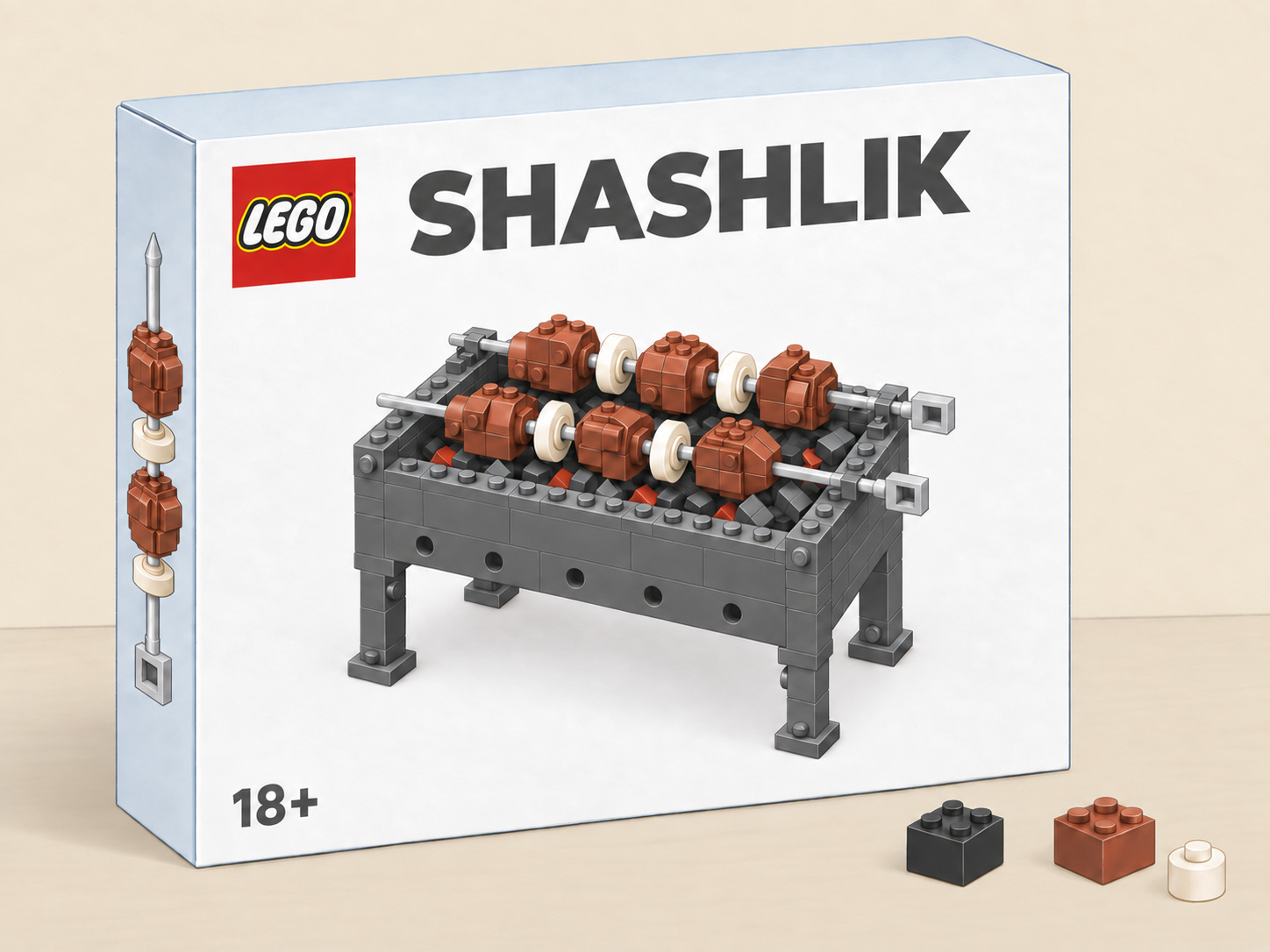 Comic: a white LEGO Shashlik box showing a brick-built grill, standing on a pale sandy table against a cream-coloured wall, with three loose bricks beside it.